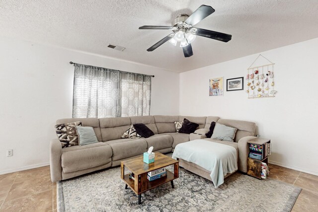 living room featuring ceiling fan with notable chandelier, a textured ceiling, and light tile patterned floors