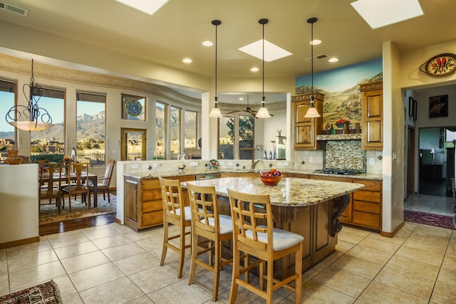 kitchen with backsplash, a kitchen breakfast bar, hanging light fixtures, kitchen peninsula, and a mountain view