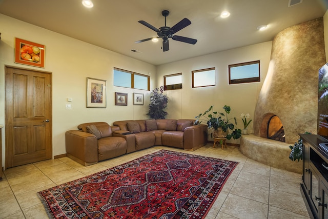 living room with light tile patterned floors, a large fireplace, and ceiling fan