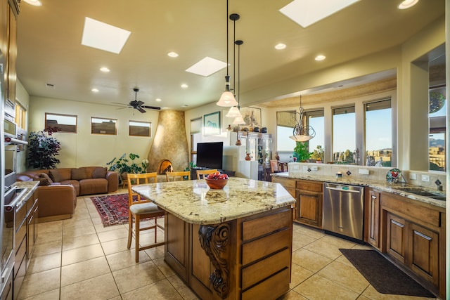 kitchen with a kitchen island, a skylight, decorative light fixtures, a kitchen breakfast bar, and stainless steel dishwasher