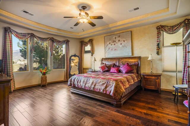 bedroom with dark hardwood / wood-style floors, a raised ceiling, and ceiling fan