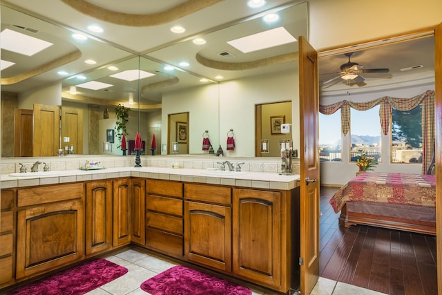 bathroom featuring vanity, tile patterned flooring, a skylight, and ceiling fan