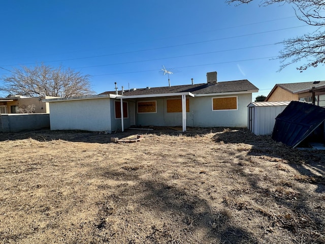 rear view of property with a storage unit