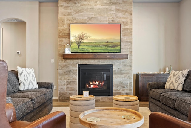 living room with a tile fireplace and light hardwood / wood-style flooring