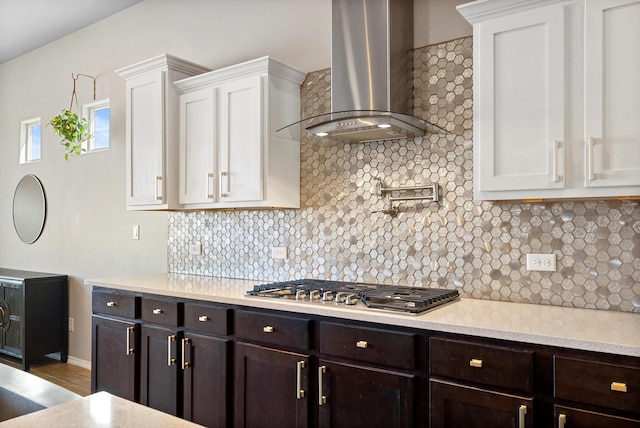 kitchen with wall chimney exhaust hood, stainless steel gas cooktop, decorative backsplash, and white cabinets