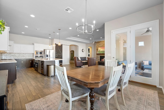 dining space featuring an inviting chandelier, wood-type flooring, and a fireplace