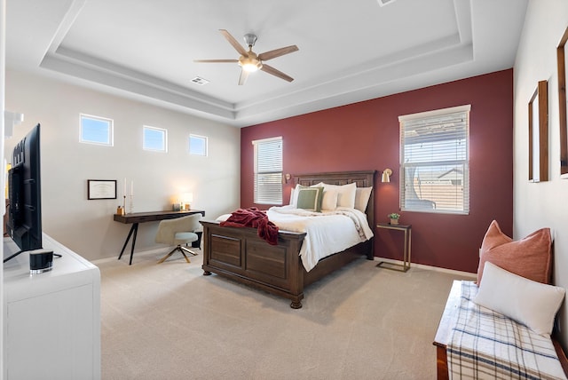 carpeted bedroom featuring a raised ceiling and ceiling fan