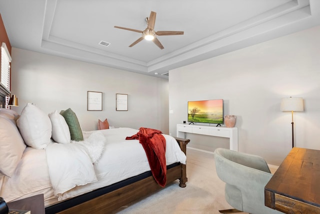 carpeted bedroom featuring ceiling fan and a tray ceiling