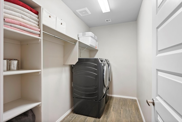 laundry area featuring separate washer and dryer and light hardwood / wood-style flooring