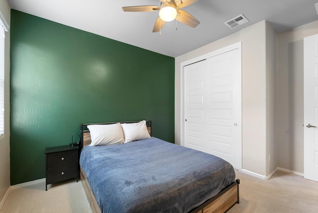 bedroom with ceiling fan, light colored carpet, and a closet