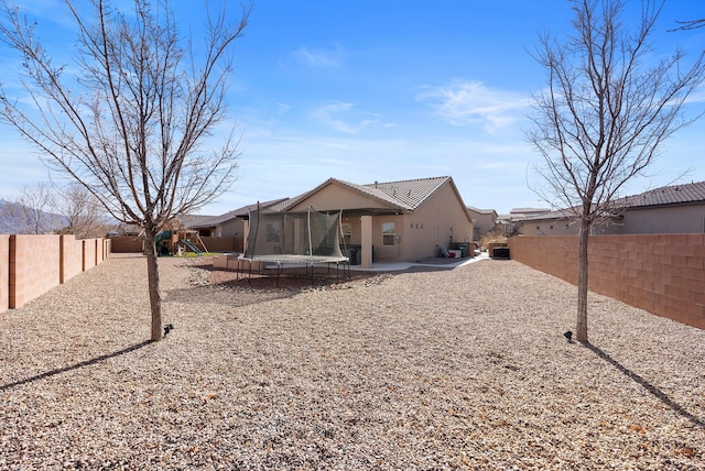 back of house with a patio and a trampoline