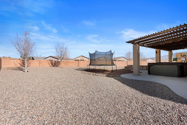 view of yard with a trampoline, a patio area, and a hot tub