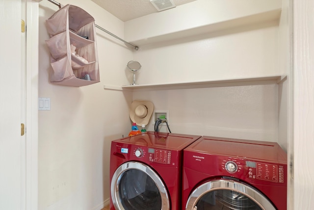 clothes washing area with washer and dryer and a textured ceiling