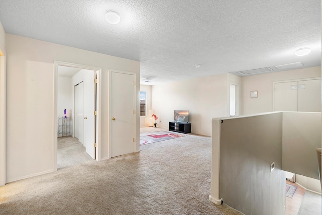 corridor featuring light carpet and a textured ceiling