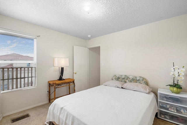 bedroom with light colored carpet, multiple windows, and a textured ceiling