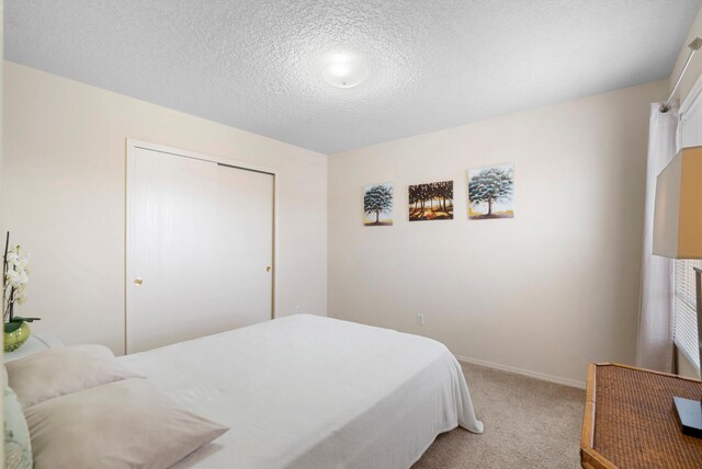 bedroom with light colored carpet, a textured ceiling, and a closet