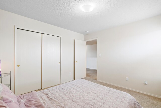 unfurnished bedroom with light carpet, a closet, and a textured ceiling