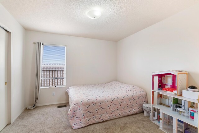 bedroom featuring light carpet and a textured ceiling