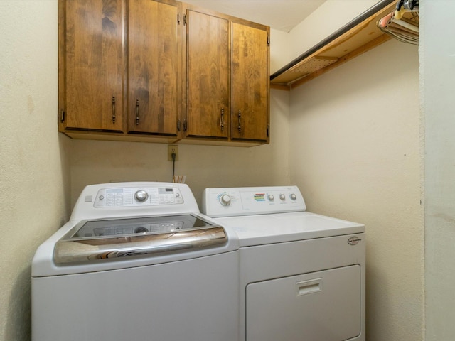 clothes washing area featuring cabinets and washing machine and clothes dryer