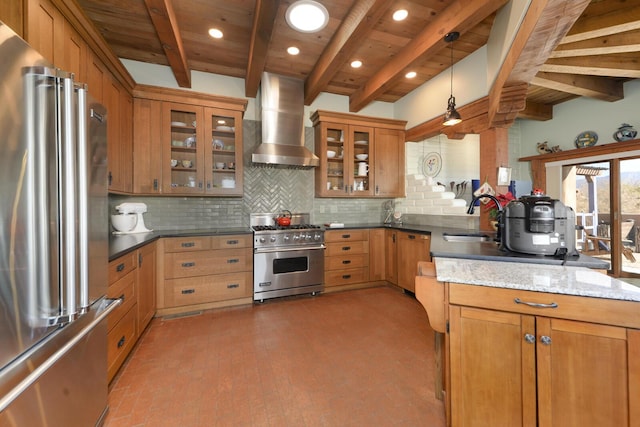 kitchen featuring wall chimney range hood, sink, hanging light fixtures, high end appliances, and tasteful backsplash