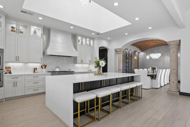 kitchen featuring a large island, white cabinetry, and custom exhaust hood