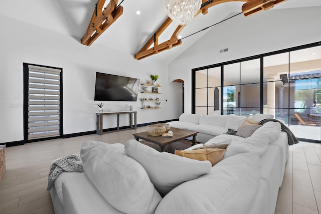 living room with beamed ceiling, high vaulted ceiling, light wood-type flooring, and a chandelier