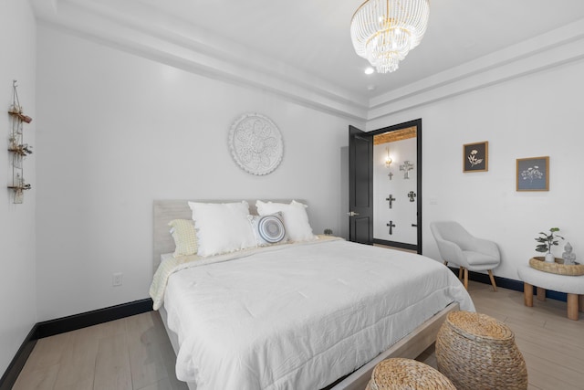 bedroom with an inviting chandelier and light hardwood / wood-style floors