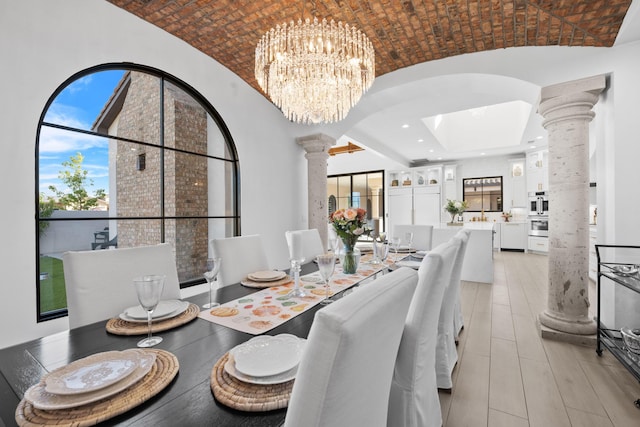 dining space with decorative columns, brick ceiling, lofted ceiling, and a chandelier