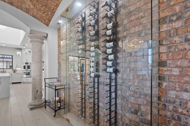 wine cellar featuring brick ceiling, lofted ceiling, and ornate columns