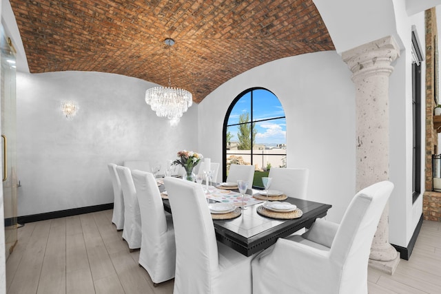 dining area featuring vaulted ceiling, decorative columns, brick ceiling, a chandelier, and light hardwood / wood-style floors