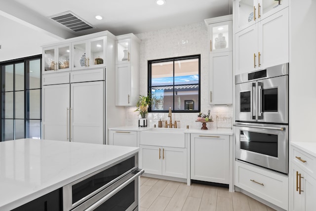 kitchen featuring white cabinetry, sink, and stainless steel double oven