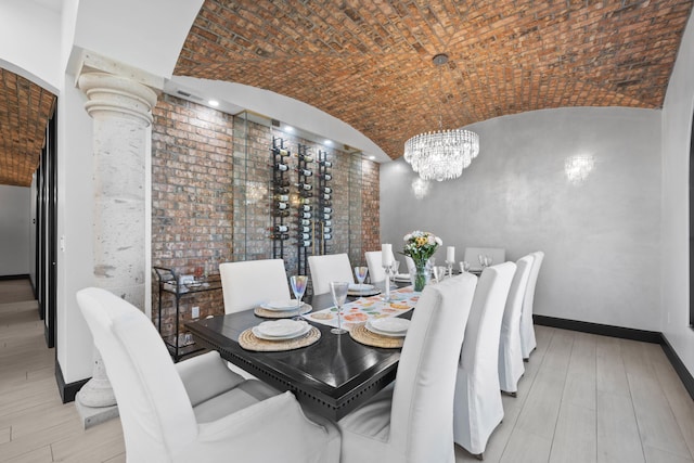 dining space featuring ornate columns, brick ceiling, lofted ceiling, and an inviting chandelier