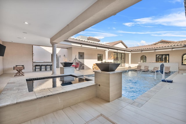 view of pool featuring a patio area, a hot tub, an outdoor bar, and pool water feature