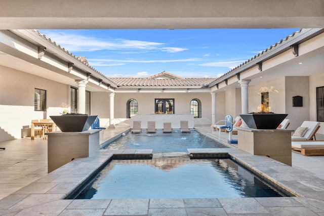 view of pool with an in ground hot tub, pool water feature, and a patio area