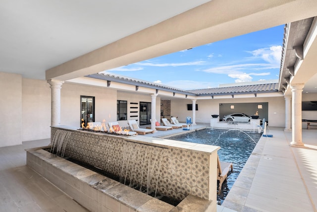 view of patio featuring pool water feature and an outdoor fire pit