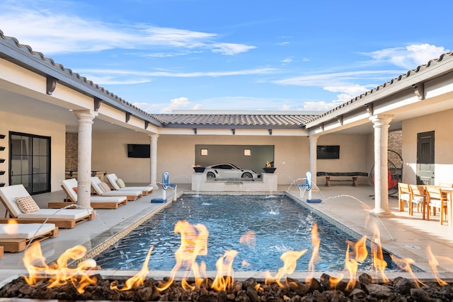 view of pool with pool water feature, an outdoor fire pit, and a patio