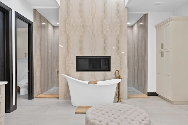 bathroom with a washtub, tile patterned flooring, and toilet