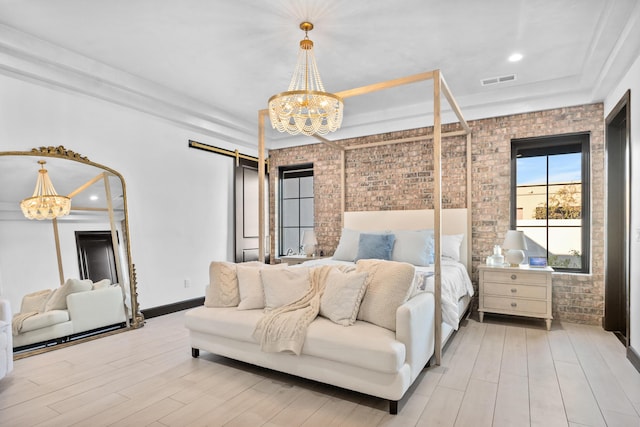 bedroom with brick wall, a barn door, a chandelier, and light hardwood / wood-style flooring