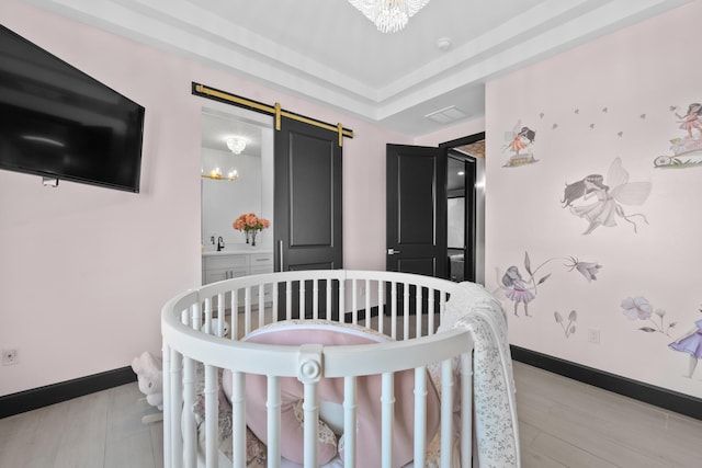 bedroom featuring a crib, a barn door, sink, and a notable chandelier