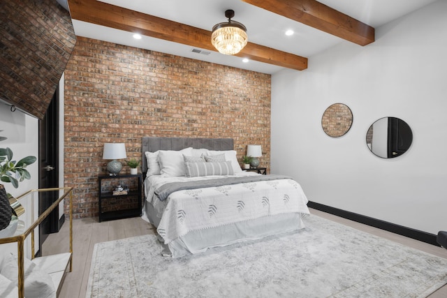 bedroom featuring beamed ceiling, brick wall, and light wood-type flooring