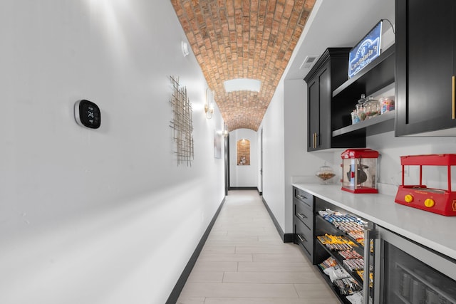 hall featuring brick ceiling, vaulted ceiling, and beverage cooler