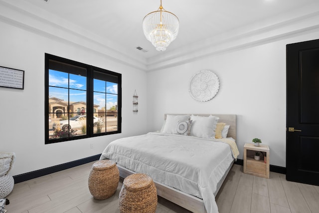 bedroom featuring an inviting chandelier and light hardwood / wood-style floors