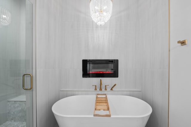 bathroom featuring independent shower and bath, tile walls, and a notable chandelier