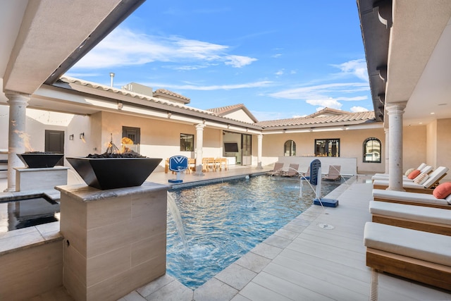 view of swimming pool with pool water feature and an outdoor fire pit