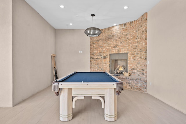 recreation room with billiards, light hardwood / wood-style floors, and a brick fireplace