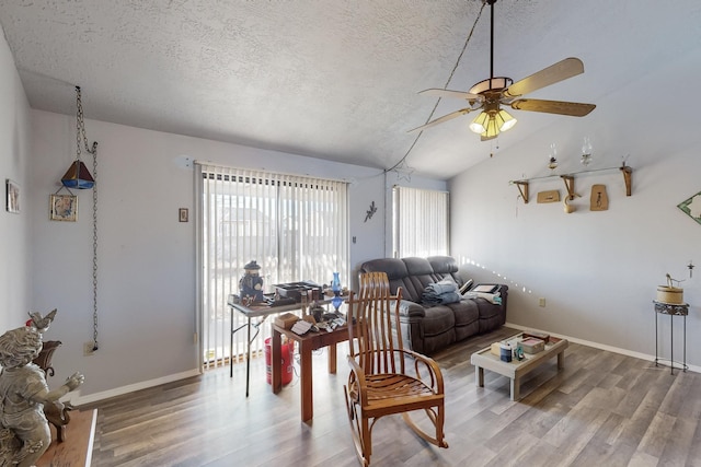 living room with ceiling fan, lofted ceiling, wood-type flooring, and a textured ceiling