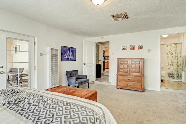 carpeted bedroom featuring a textured ceiling and ensuite bathroom