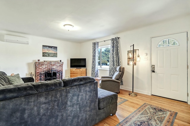 living room with a brick fireplace, hardwood / wood-style floors, and an AC wall unit