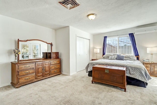 carpeted bedroom featuring a wall unit AC, a closet, and a textured ceiling