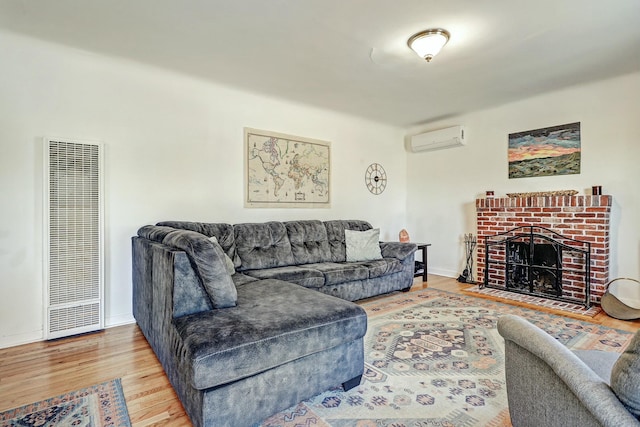 living room featuring hardwood / wood-style flooring, a wall mounted AC, and a brick fireplace